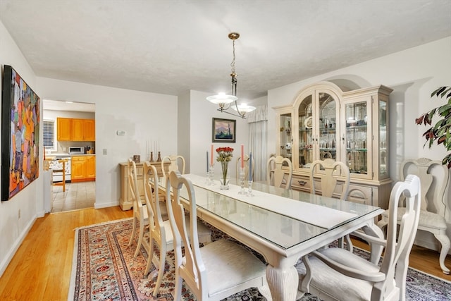 dining room with light wood-type flooring and a notable chandelier