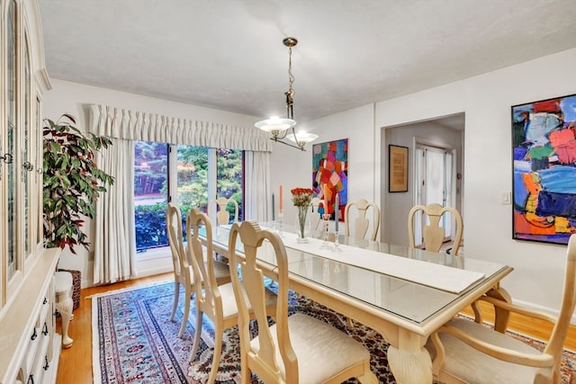 dining area with light wood-type flooring and an inviting chandelier