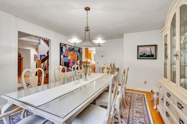 dining area with light wood-type flooring, a notable chandelier, and a textured ceiling