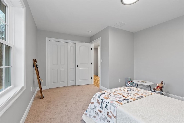 bedroom with light carpet, a closet, and multiple windows