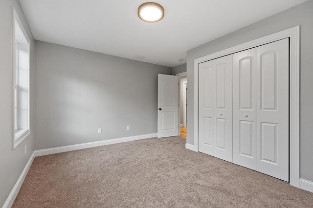 unfurnished bedroom featuring light carpet and a closet