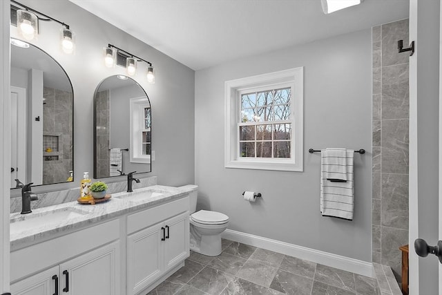 bathroom featuring a tile shower, vanity, and toilet