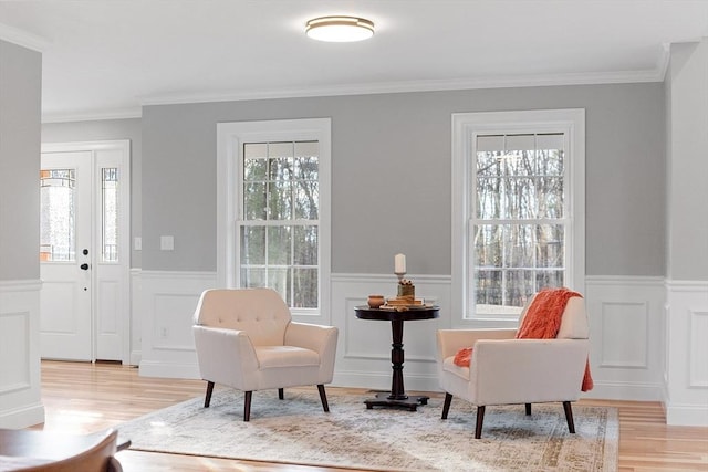 living area with light wood-type flooring, plenty of natural light, and crown molding