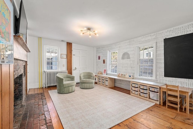 living room with radiator, wood-type flooring, and a brick fireplace