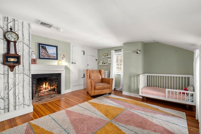 interior space with hardwood / wood-style flooring, lofted ceiling, and a crib