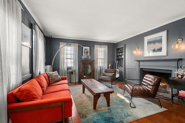 living room featuring built in shelves, ornamental molding, and hardwood / wood-style flooring