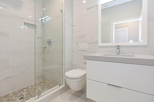 60 Newbury St Unit 10, Quincy, MA 02171 - bathroom featuring a shower stall, vanity, toilet, marble look tile flooring, and tile walls