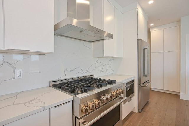 60 Newbury St Unit 10, Quincy, MA 02171 - kitchen featuring wall chimney exhaust hood, high quality appliances, white cabinets, modern cabinets, and light wood-style floors