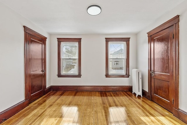 interior space with baseboards, radiator heating unit, plenty of natural light, and light wood-style floors