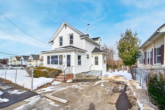 view of front of house featuring entry steps, a shingled roof, fence, and a residential view