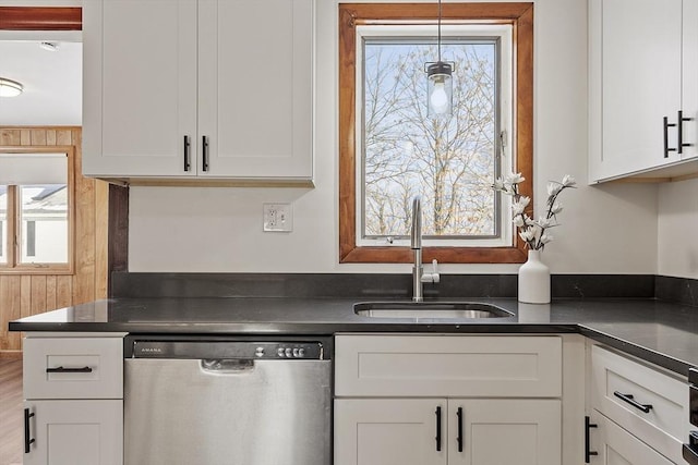 kitchen featuring dark countertops, white cabinets, a sink, and stainless steel dishwasher