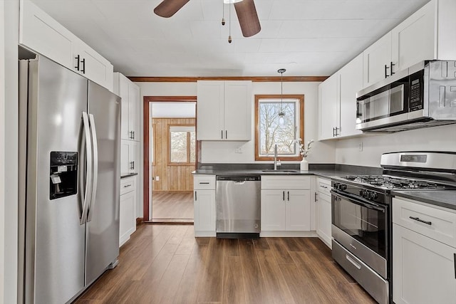 kitchen with dark countertops, white cabinets, stainless steel appliances, and a sink