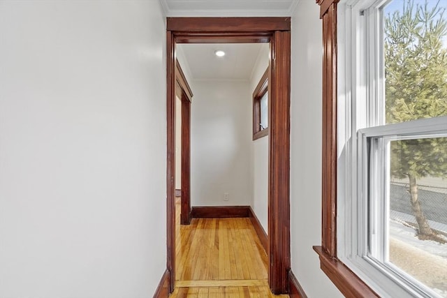 hallway featuring light wood-style floors, ornamental molding, and baseboards