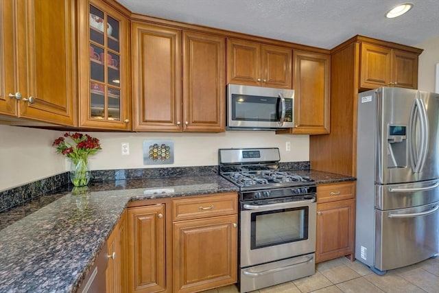 3 White Tail Dr, Tyngsborough, MA 01879 - kitchen featuring appliances with stainless steel finishes, brown cabinets, glass insert cabinets, dark stone counters, and a textured ceiling
