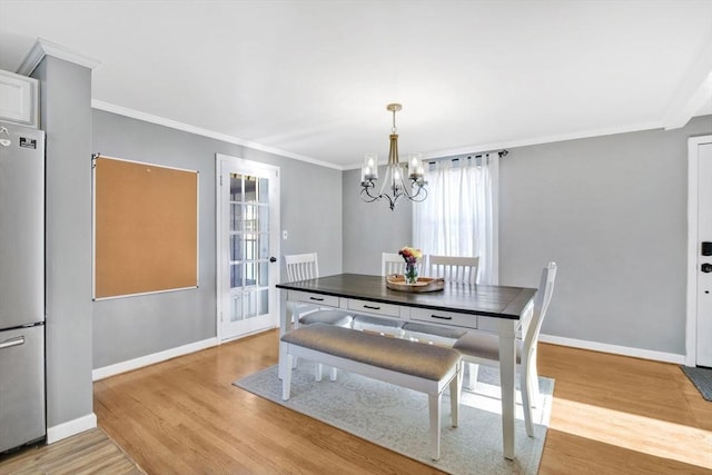 dining space with crown molding, an inviting chandelier, and light hardwood / wood-style floors