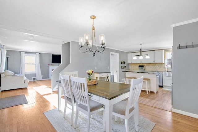 dining room with ornamental molding, a chandelier, and light hardwood / wood-style floors