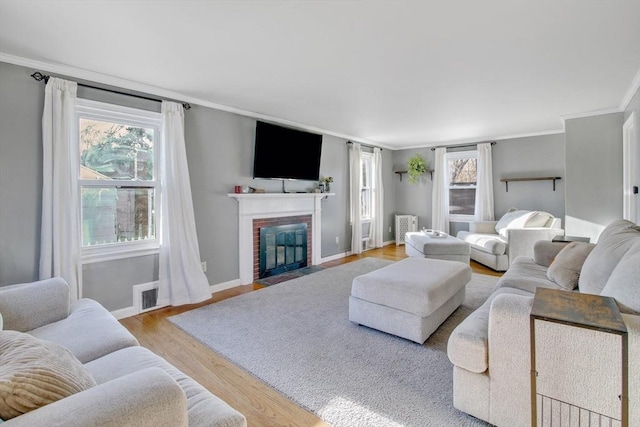 living room featuring a brick fireplace, light hardwood / wood-style flooring, and ornamental molding