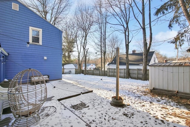 yard covered in snow featuring a storage shed