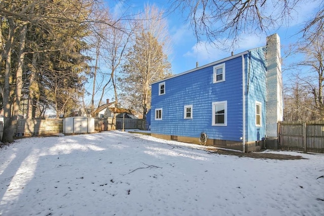 snow covered back of property with a storage shed