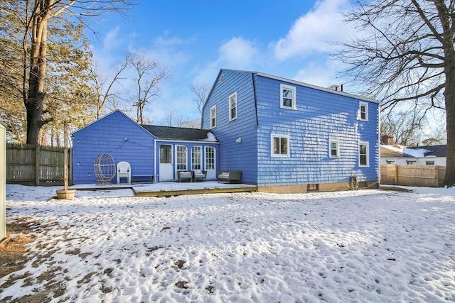 snow covered rear of property with a wooden deck