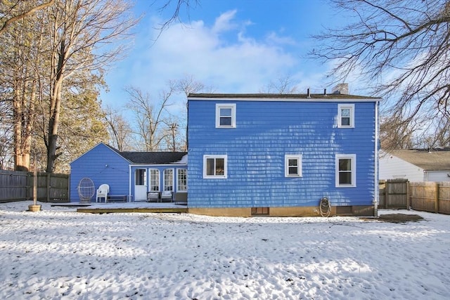 snow covered rear of property with a wooden deck