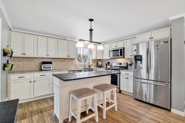 kitchen featuring stainless steel appliances, white cabinetry, a center island, and pendant lighting