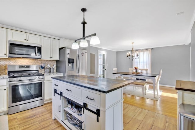 kitchen with pendant lighting, stainless steel appliances, a center island, and white cabinets