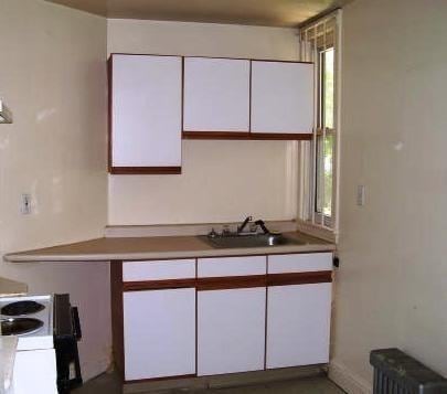 14 Bellevue St, Boston, MA 02125 - kitchen with radiator heating unit, white cabinets, electric stove, and light countertops