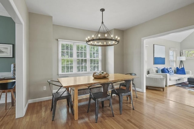 dining space with light wood-type flooring, baseboards, a chandelier, and a healthy amount of sunlight