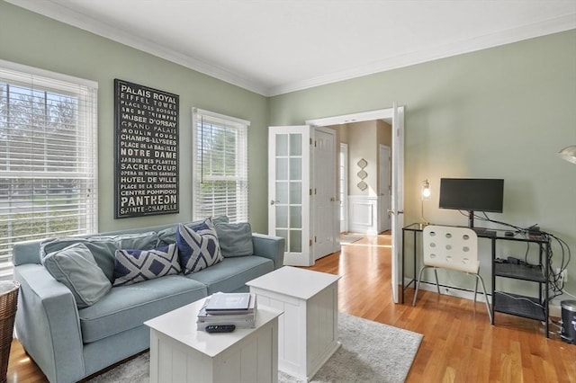living area with ornamental molding, french doors, and light wood-type flooring