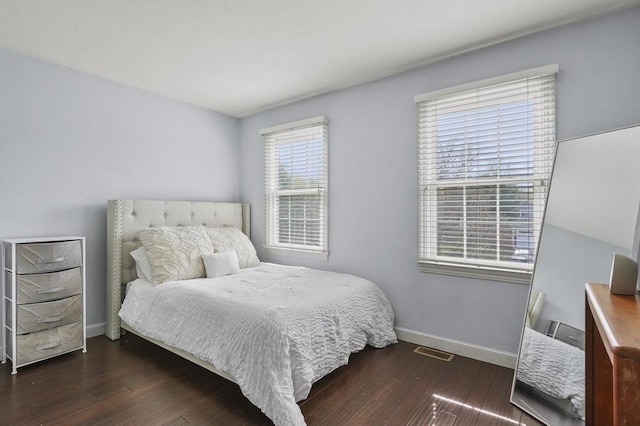 bedroom with baseboards, wood finished floors, and visible vents