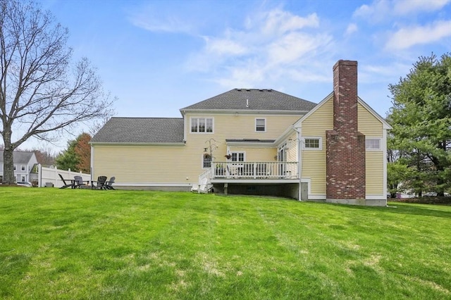 back of property featuring a chimney, roof with shingles, a yard, and a deck