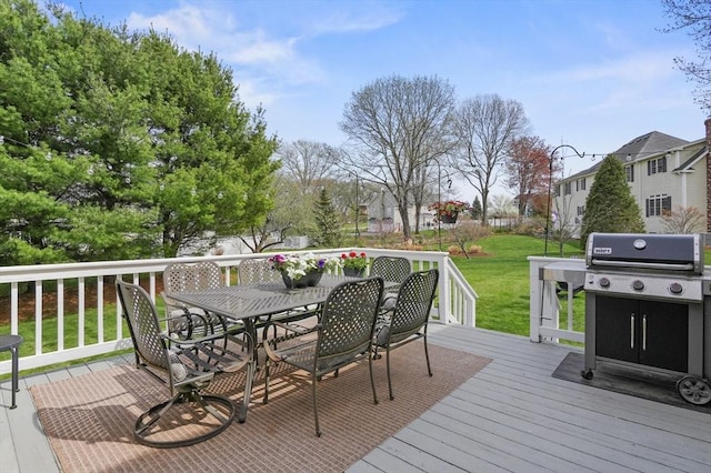 wooden terrace featuring a lawn, outdoor dining area, and area for grilling