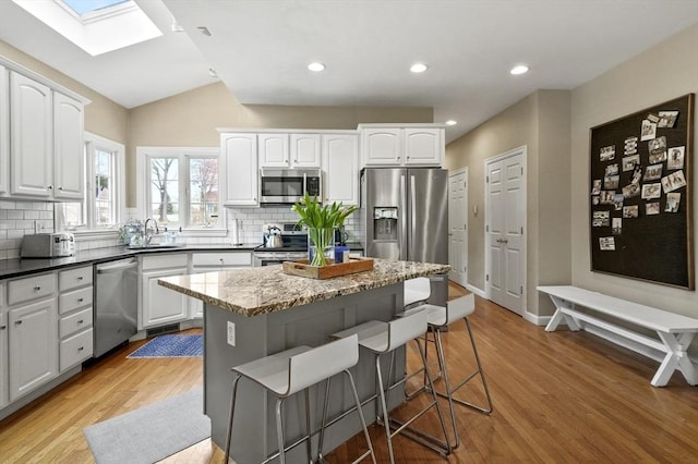 kitchen with a sink, appliances with stainless steel finishes, a breakfast bar, and backsplash