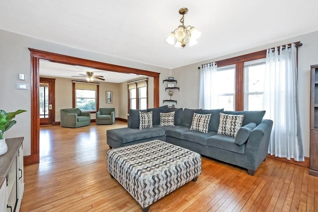 living area featuring baseboards, a notable chandelier, and light wood finished floors