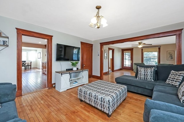 living room featuring an inviting chandelier, light wood-style flooring, and baseboards