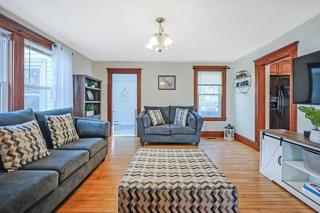 living room featuring a baseboard radiator, baseboards, a notable chandelier, and light wood finished floors