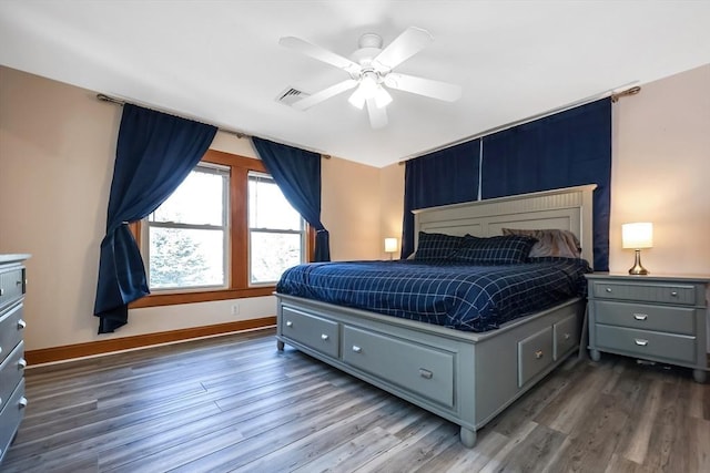 bedroom with visible vents, a ceiling fan, baseboards, and wood finished floors