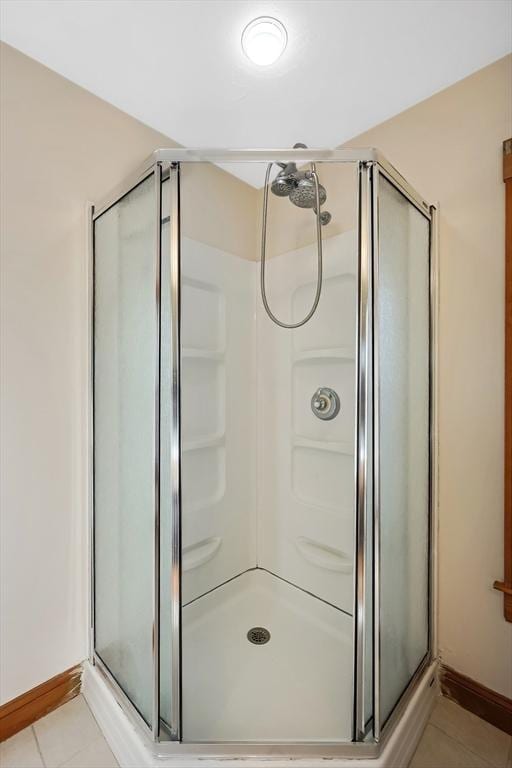 bathroom with tile patterned flooring, a shower stall, and baseboards