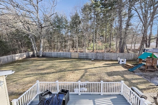 wooden deck featuring a playground, a yard, and a fenced backyard