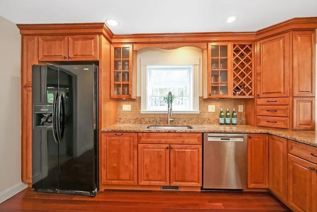 kitchen featuring a sink, dishwasher, dark wood finished floors, and black fridge