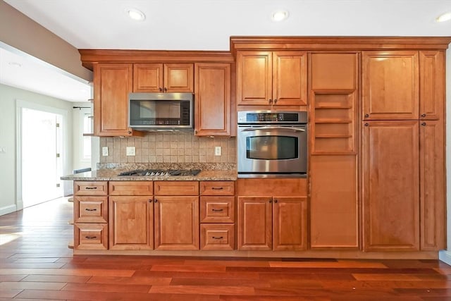 kitchen featuring light stone counters, backsplash, light wood-style flooring, and appliances with stainless steel finishes