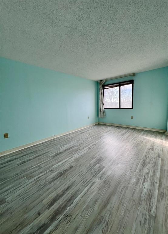 empty room with wood-type flooring and a textured ceiling