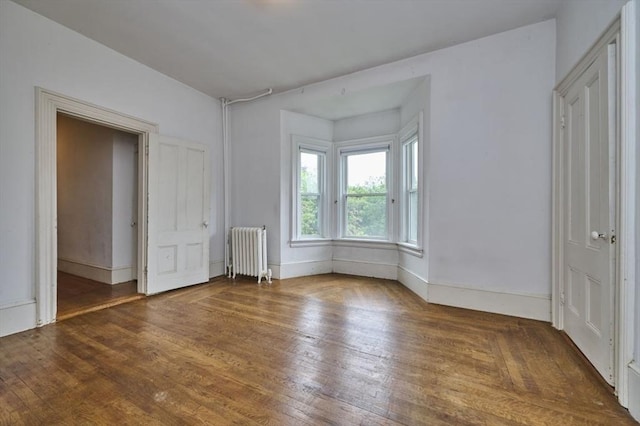unfurnished bedroom featuring radiator heating unit, wood finished floors, and baseboards
