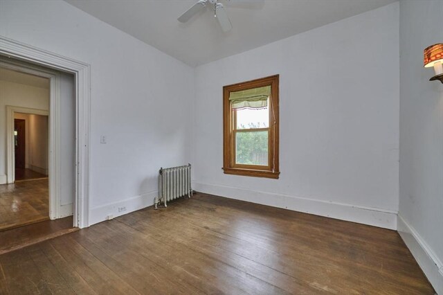 unfurnished room with radiator heating unit, hardwood / wood-style flooring, a ceiling fan, and baseboards