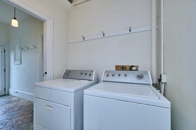clothes washing area with washing machine and clothes dryer and stone finish floors