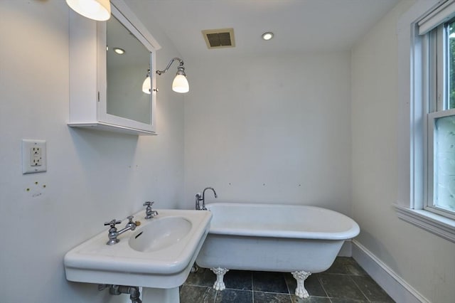bathroom featuring a soaking tub, recessed lighting, a sink, and baseboards