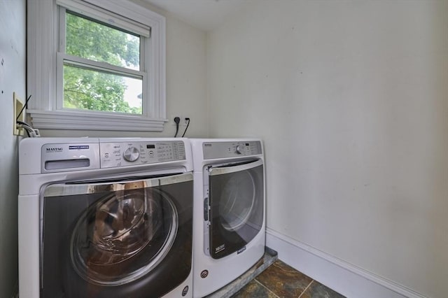 washroom featuring independent washer and dryer, baseboards, and dark stone finish flooring