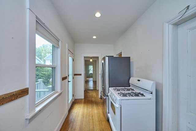 kitchen featuring white range with gas cooktop, light wood-style floors, recessed lighting, and baseboards