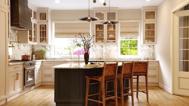 kitchen with a center island, light stone counters, light hardwood / wood-style floors, and premium range hood